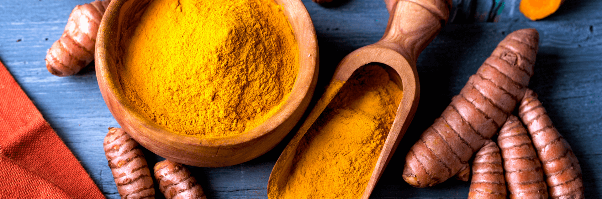 benefits of turmeric in TCM - image of ground turmeric in bowl next to roots cut to display bright orange color
